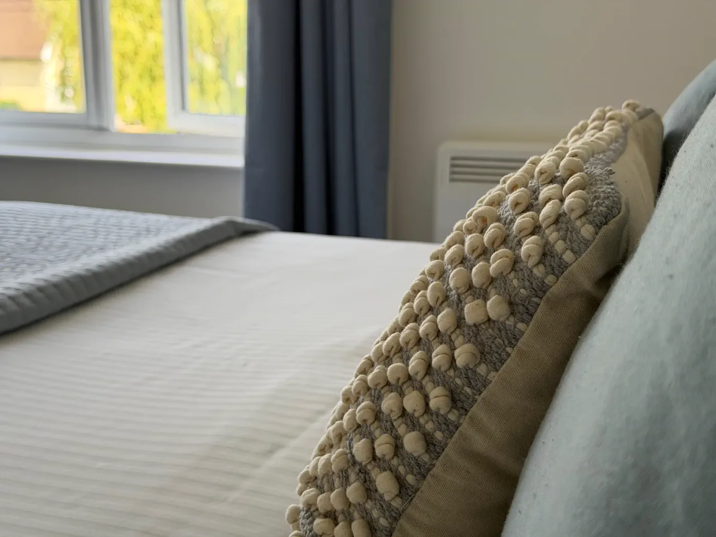 A cushion styling detail in Bedroom 1 at Green Woodpecker Lodge