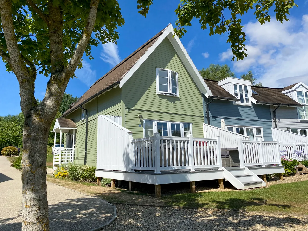 Green Woodpecker Lodge — a green timber-clad lodge with a white deck on Isis Lake