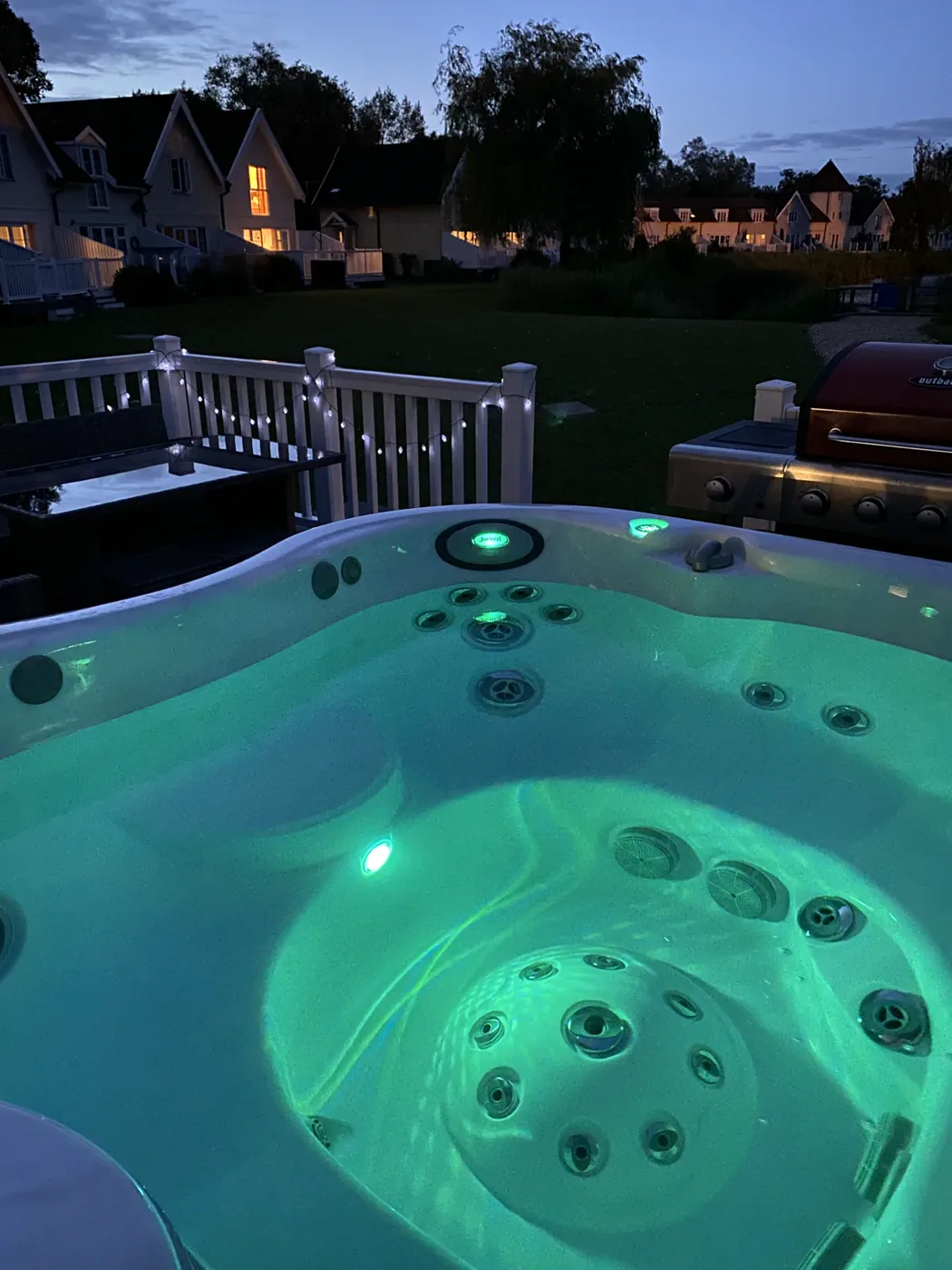 The hot tub lit up on the deck at Green Woodpecker Lodge in the evening